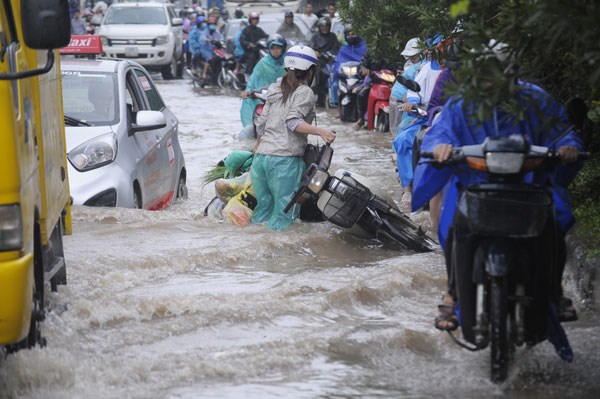 Người dân vất vả vượt qua chỗ ngập đoạn đường gom đại lộ Thăng Long, gần lối vào khu độ thị mới Lê Trọng Tấn - Geleximco (ảnh chụp ngày 21/7/2018) - Ảnh: Khánh Linh