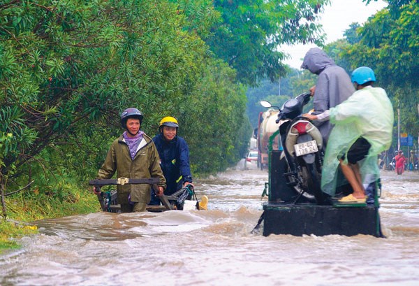 Người dân chỉ còn cách sử dụng dịch vụ vận chuyển thô sơ qua đoạn ngập sâu ở đường gom đại lộ Thăng Long (Ảnh chụp sau trận mưa lớn ngày 21/7/2018) - Ảnh: Khánh Linh